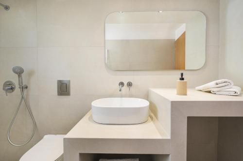 a white bathroom with a sink and a mirror at Einalia Holiday Homes by the Beach in Kardamaina