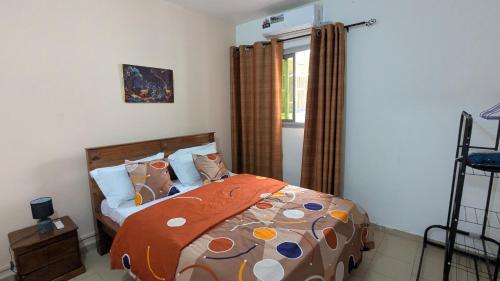 a bedroom with a bed with an orange comforter and a window at LANISCA'S Home in Yaoundé