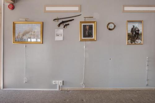 a white wall with three pictures and a clock on it at Seglarhotellet Käringön in Käringön
