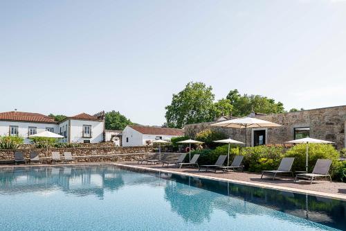a large swimming pool with chairs and umbrellas at Hotel Paço de Vitorino in Ponte de Lima