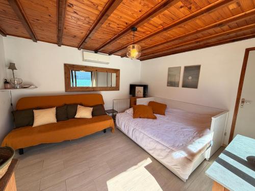 a bedroom with two beds and a wooden ceiling at La cabane les pieds dans l'eau, accès direct au lac d'Annecy in Doussard