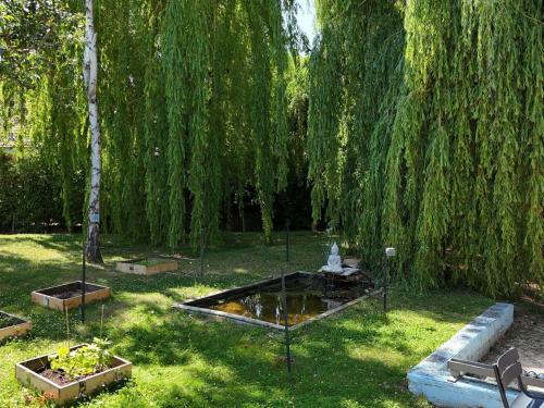 a park with a weeping willow tree and a pond at ibis Metz Nord in Woippy