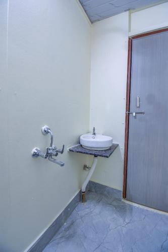 a white bathroom with a sink and a door at Hotel Briko Lodging & Resort in Nashik
