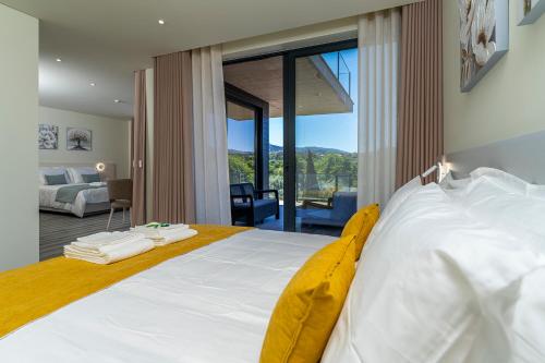 a bedroom with a white bed with a large window at Lima Riverview Suites in Ponte de Lima