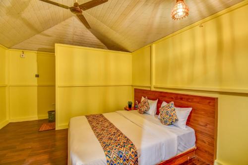a bedroom with a bed with yellow walls and a ceiling at Hotel Briko Lodging & Resort in Nashik