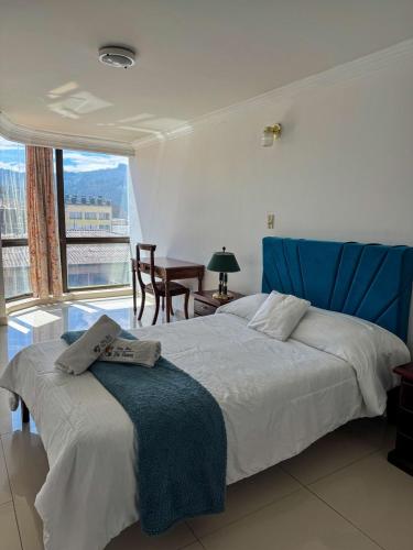 a bedroom with a large bed with a blue headboard at HOTEL REALPICO VICTORIA in Duitama