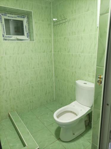 a bathroom with a toilet and a shower with a window at All Home in Cholpon-Ata