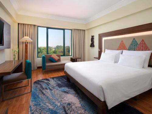 a hotel room with a bed and a television at Novotel Solo in Solo