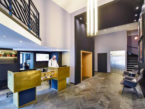 a man standing at a counter in a lobby at ibis Styles Dijon Central in Dijon
