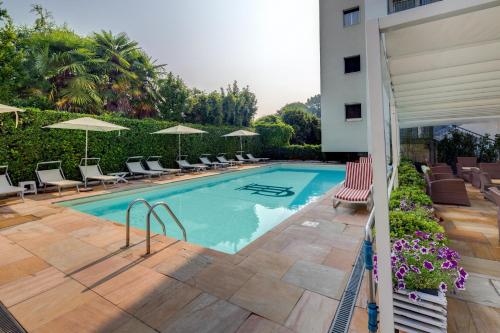 ein Schwimmbad mit Liegestühlen und Sonnenschirmen neben einem Gebäude in der Unterkunft Jet Hotel, Sure Hotel Collection by Best Western in Gallarate