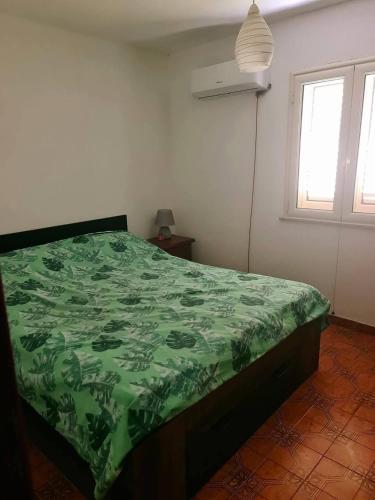 a bedroom with a green comforter on a bed at Casa vacanze a Roccella Jonica in Roccella Ionica