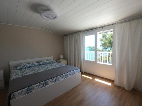 a bedroom with a bed and a large window at Seaside Apartments Sunny Prižba in Blato