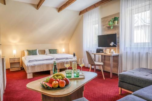 a room with a bed and a table with a bowl of fruit at Hotel Slunce - wellness s bazénem, pivovar Morous a bowling in Rýmařov