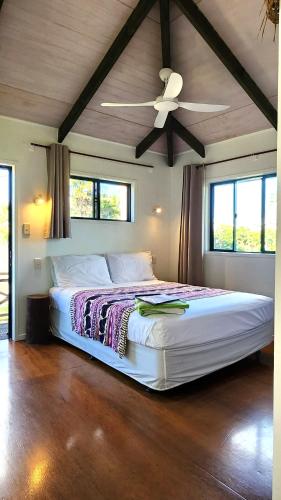 a bedroom with a bed with a ceiling fan at Aroa Kainga Bungalows and Apartment in Rarotonga