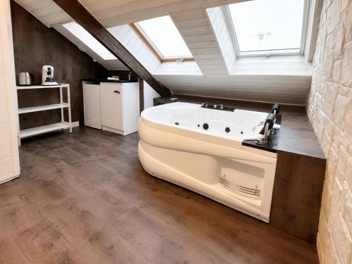 a bathroom with a large white bath tub in a attic at L'Opale - Sauna et Jacuzzi in Dijon