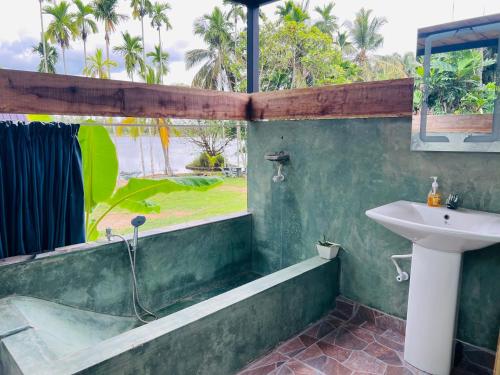 a bathroom with a sink and a bath tub and a window at Lake Cabana in Udawalawe