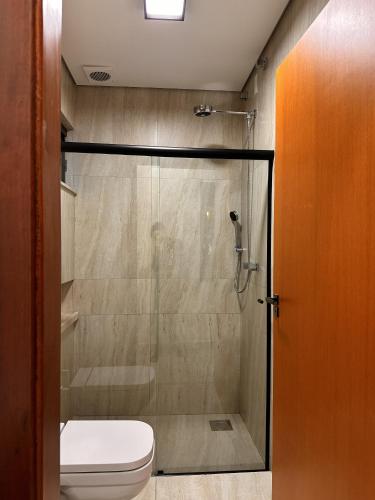 a bathroom with a glass shower with a toilet at Pousada Jamacaii in Araxá