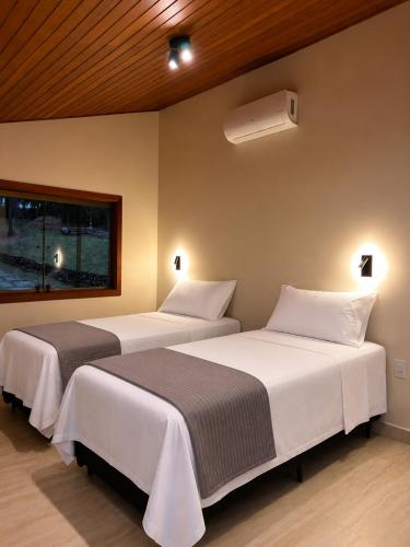 two beds sitting next to each other in a room at Pousada Jamacaii in Araxá