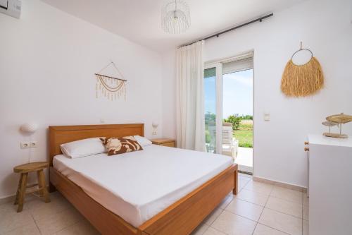 a bedroom with a bed and a large window at Einalia Holiday Homes by the Beach in Kardamaina