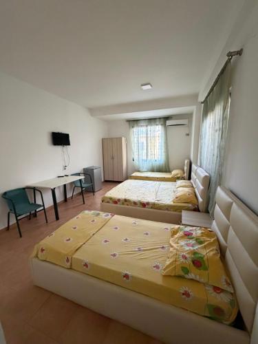 a bedroom with two beds and a desk and a table at Hotel Parking Pika in Shëngjin