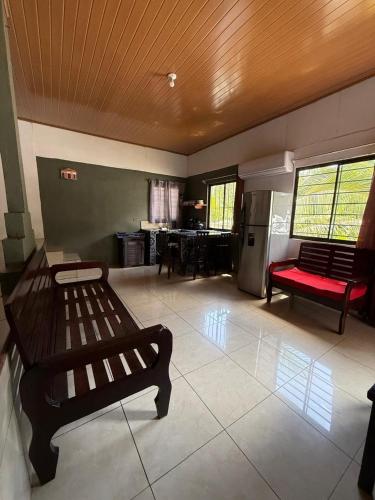 a living room with two benches and a kitchen at Cabinas Chinchilla in Quepos