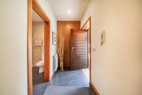 a bathroom with a toilet and a wooden door at Casa do Rego - by Proguest in Valdosende