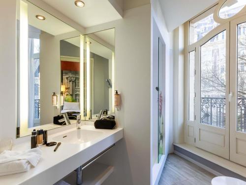 a bathroom with a sink and a large mirror at Mercure Lille Centre Grand Place in Lille