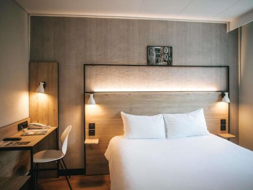 a hotel room with a large bed and a desk at ibis Limoges Centre in Limoges