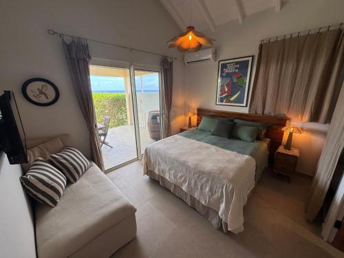 a bedroom with a bed and a couch and a window at Villa JAUNE in Oyster Pond