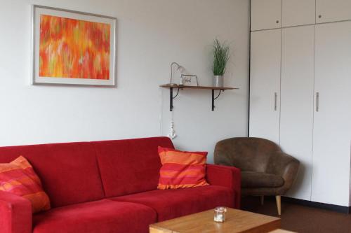 a living room with a red couch and a chair at Nordnordwest in Langeoog