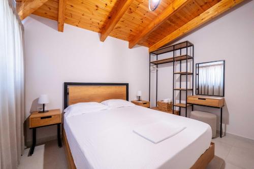 a bedroom with a large white bed and a wooden ceiling at Crown Villa in Sarandë
