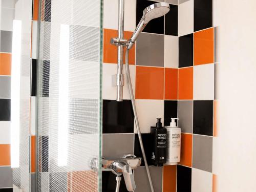 a bathroom with a shower with black and orange tiles at ibis Styles Caen Centre Historique in Caen