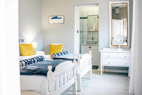 a white bedroom with two beds and a mirror at Lalandi 14 - Beachfront Self-Catering- Langstrand Walvis Bay in Langstrand