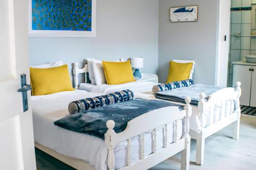 two white beds in a room with yellow pillows at Lalandi 14 - Beachfront Self-Catering- Langstrand Walvis Bay in Langstrand