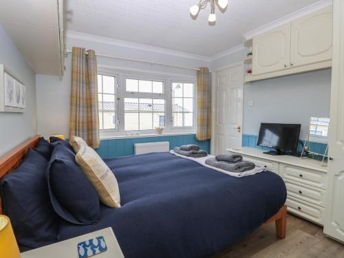 a bedroom with a blue bed and a television at Seaward in Norwich