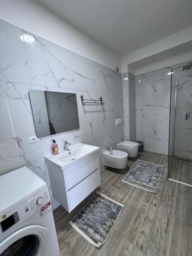 a bathroom with a sink and a washing machine at Angelo Apartments Ilyonis Residence in Shëngjin
