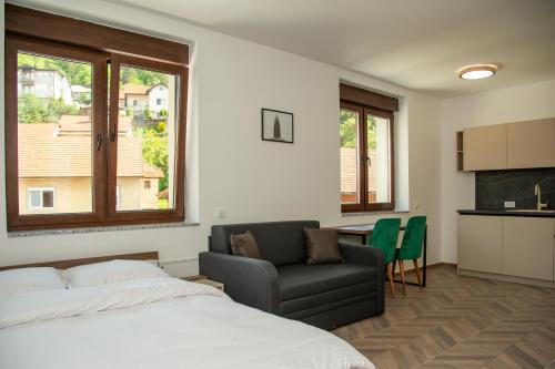 a bedroom with a bed and a couch and a kitchen at Apartmani Gradska in Prijepolje