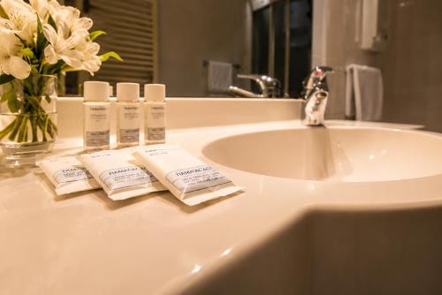 Ein Waschbecken im Badezimmer mit zwei Handtüchern und einer Vase mit Blumen in der Unterkunft Hotel Posta in Cecina