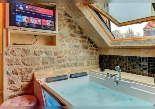 a large bath tub in a bathroom with a window at Sous mon toit - Sauna & jacuzzi in Dijon
