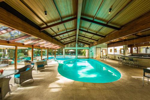a large swimming pool with chairs and a table at Bavaria Sport Hotel in Gramado