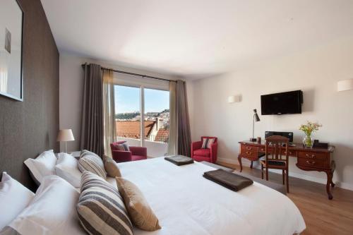 a hotel room with a bed and a desk and a window at Casa Balthazar in Lisbon