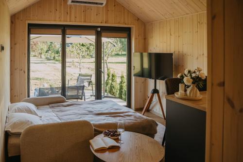 a bedroom with a bed and a television and a table at Ruoliškis tiny house in Biržai