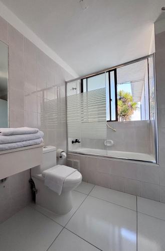 a bathroom with a toilet and a tub and a window at Hotel Camino del Alto Reñaca in Viña del Mar
