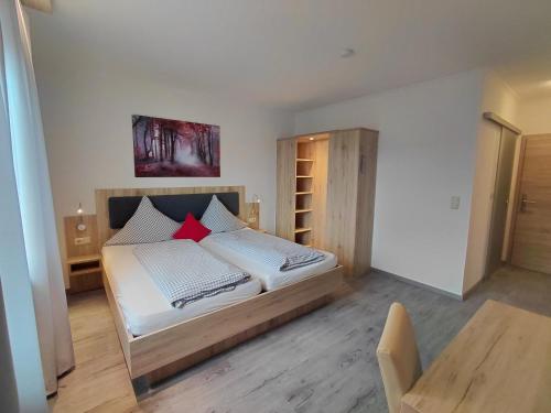 a bedroom with a bed with white sheets and red pillows at Pension Karin in Breitengüßbach