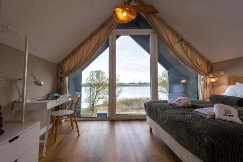 a bedroom with a bed and a desk and a large window at Sen Topoli - Domy nad jeziorem I Sauna I Plaża I 30 min od Torunia in Mirakowo