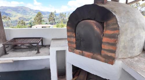 a pizza oven with a table and a bench at Lodge La Ilusión in Ibarra