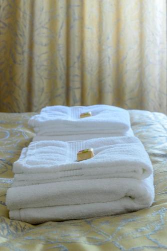 four towels are stacked on top of a bed at Kaposvár Deluxe Apartman in Kaposvár