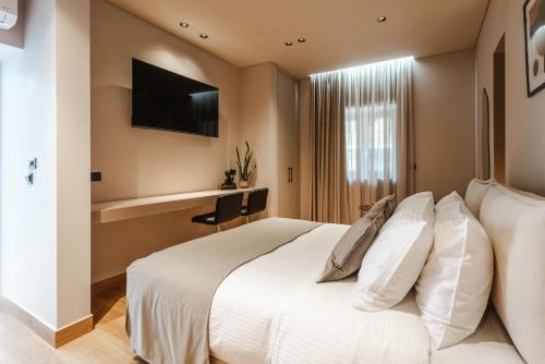 a bedroom with a white bed and a desk at Grava Aurum - City Suites in Igoumenitsa