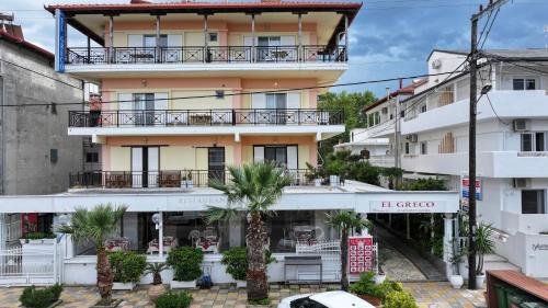 an apartment building with a balcony and palm trees at El Greco Nei Pori in Nei Poroi