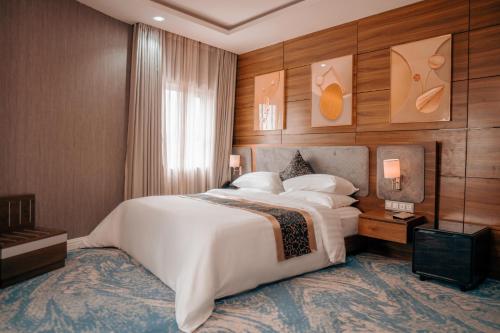 a bedroom with a large white bed and wooden walls at Swisse International Rancho Valeria Hotel & Suites in Warri